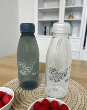 Botellas reutilizables de Amnistía Internacional sobre mesa con frutas frescas